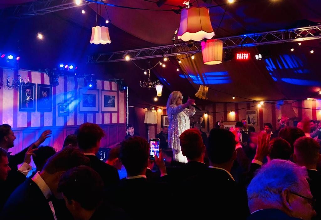 Zangeres treedt op voor publiek onder schemerlampen en podiumlicht