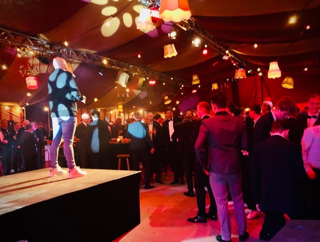 Artiest op een podium tussen feestende gasten in de bruine kroeg